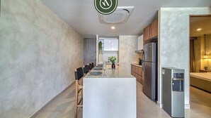 A modern kitchen with a central island, stainless steel appliances, and a dining area with chairs.