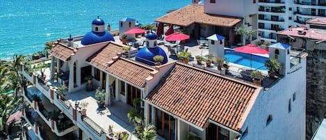 Un hotel con piscina, cúpulas azules y vistas al mar.