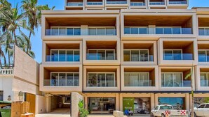 A multi-story hotel with a modern design, featuring balconies on each floor and a visible restaurant at the ground level. - New 1 BR Condo with Amazing Rooftop Pool - Jacuzzi (Bucerías)