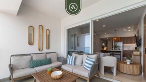 Ein modernes Wohnzimmer mit Sofa, Couchtisch und dekorativen Spiegeln. Eine Glastür zum Verschieben führt in einen Küchenbereich.