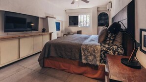 A bedroom with a bed, a TV, a ceiling fan, a window, and a door. - Cozy 2BR King beds - Rooftop Pool - Fast WiFi (Puerto Vallarta)