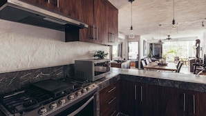 A modern kitchen with dark wood cabinets, a stainless steel stove, and a microwave. - Cozy 2BR King beds - Rooftop Pool - Fast WiFi (Puerto Vallarta)