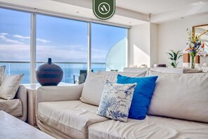 A modern living room with a large window offering a view of the sea.