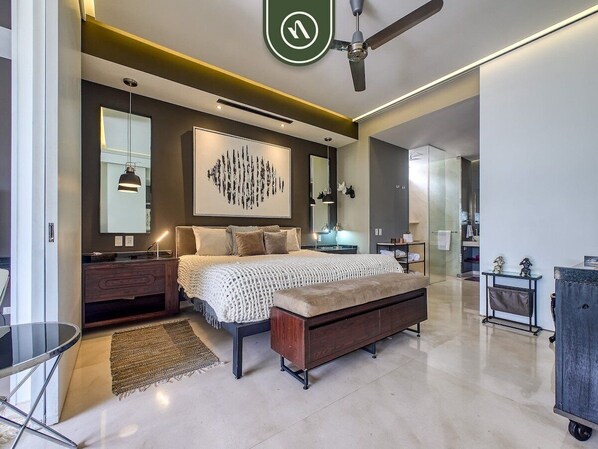 A modern bedroom with a large bed, bedside tables, a bench, a ceiling fan, and a large abstract artwork on the wall.