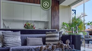 Una sala de estar moderna con un sofá, almohadones decorativos, una mesa de centro de vidrio y una escultura.