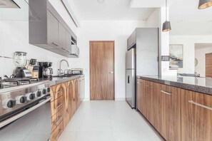 A modern kitchen with a built-in oven, a refrigerator, and wooden cabinets.