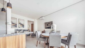A modern kitchen with a wooden island, grey upholstered chairs, and artwork on the walls. - DellaTerra 1A | 2BR/2BA Nuevo Nayarit | Pool & WiFi (Bucerías)