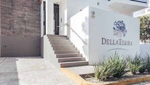 A modern building entrance with a staircase leading to a door marked "1-B". - DellaTerra 1A | 2BR/2BA Nuevo Nayarit | Pool & WiFi (Bucerías)
