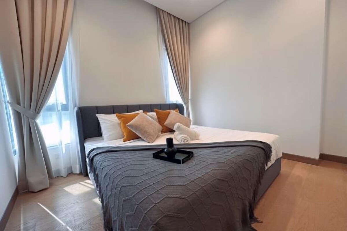 Ein modernes Hotelzimmer mit einem großen Bett, beigen Vorhängen und Blick ins Freie.