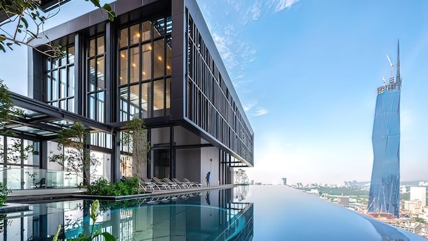 Een modern gebouw met grote ramen en een zwembad dat tot aan de rand van het perceel loopt.