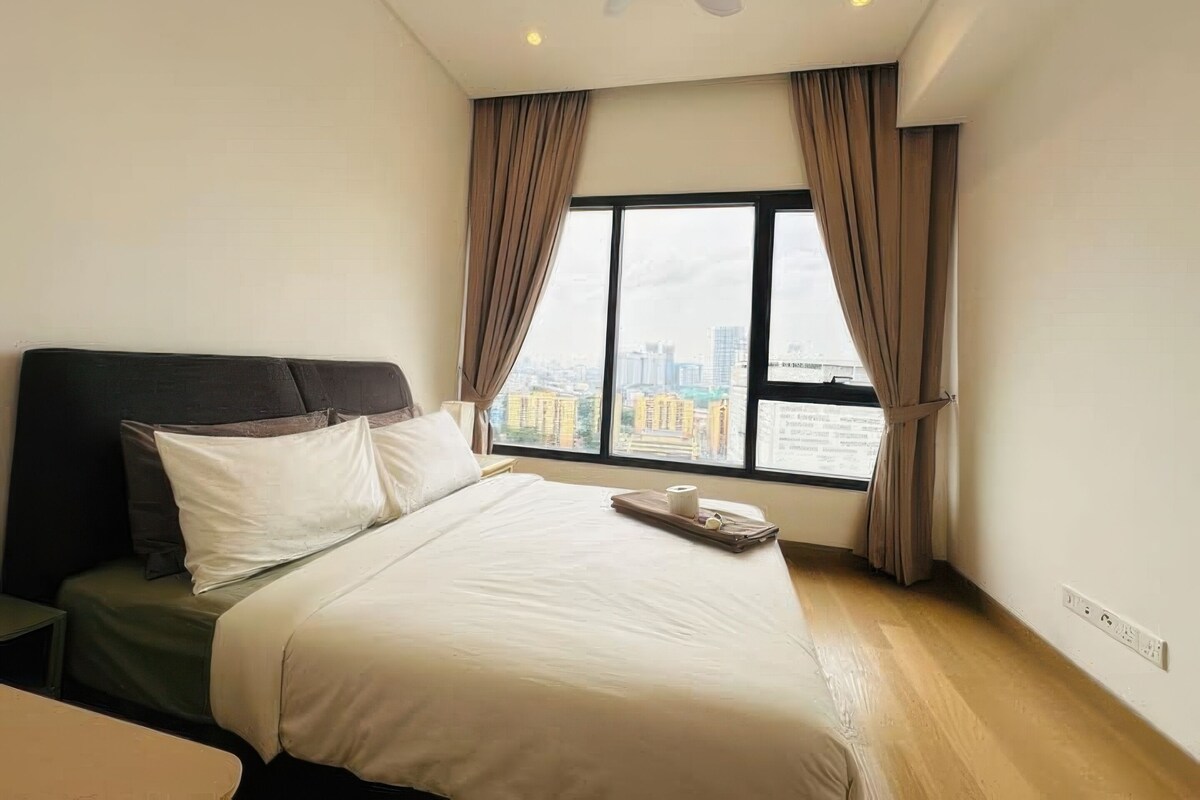 A hotel room with a bed, a ceiling fan, a window with curtains, and a city view.