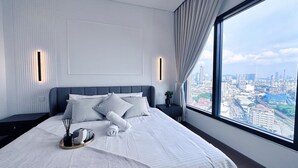 Een moderne hotelkamer met een groot bed, stadszicht en nachtkastje met lamp.