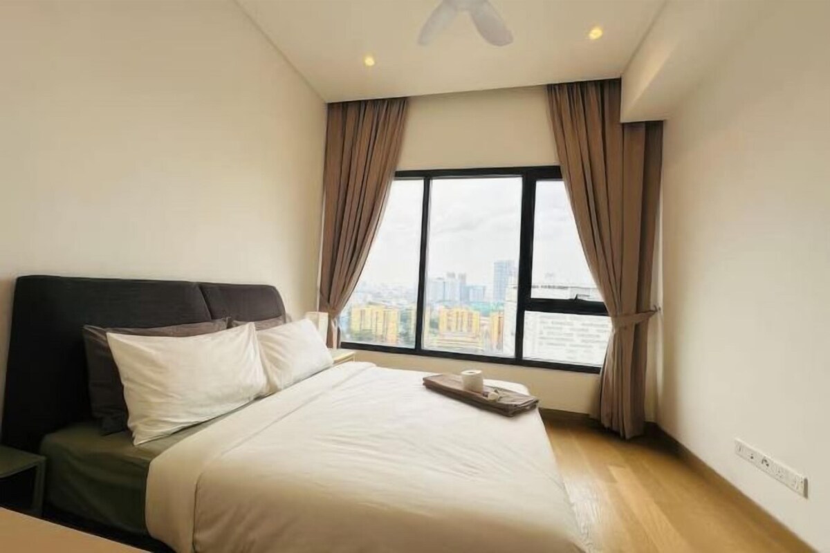 Ein Hotelzimmer mit Bett, einem fenster mit Vorhängen, einem Deckenventilator und Blick auf eine Stadtlandschaft.
