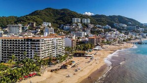 Eine Küstenstadt mit Strand, Hotels und einem bergigen Hintergrund.