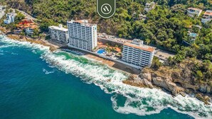 Un hotel costero con varias edificaciones, piscina y zona de playa.