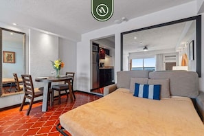 A hotel room with a bed, a dining table with chairs, a kitchen area, and a view of the outside. - Beachfront Puerto Vallarta Studio w/ Pool & WiFi (Puerto Vallarta)