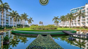 Un hotel con piscina, palmeras y un césped cuidado.