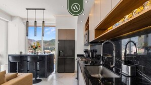 Een moderne keuken met een zwart aanrecht, roestvrijstalen apparatuur en een bar met krukken.