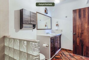 Un baño con inodoro, tocador, espejo y puerta de madera.