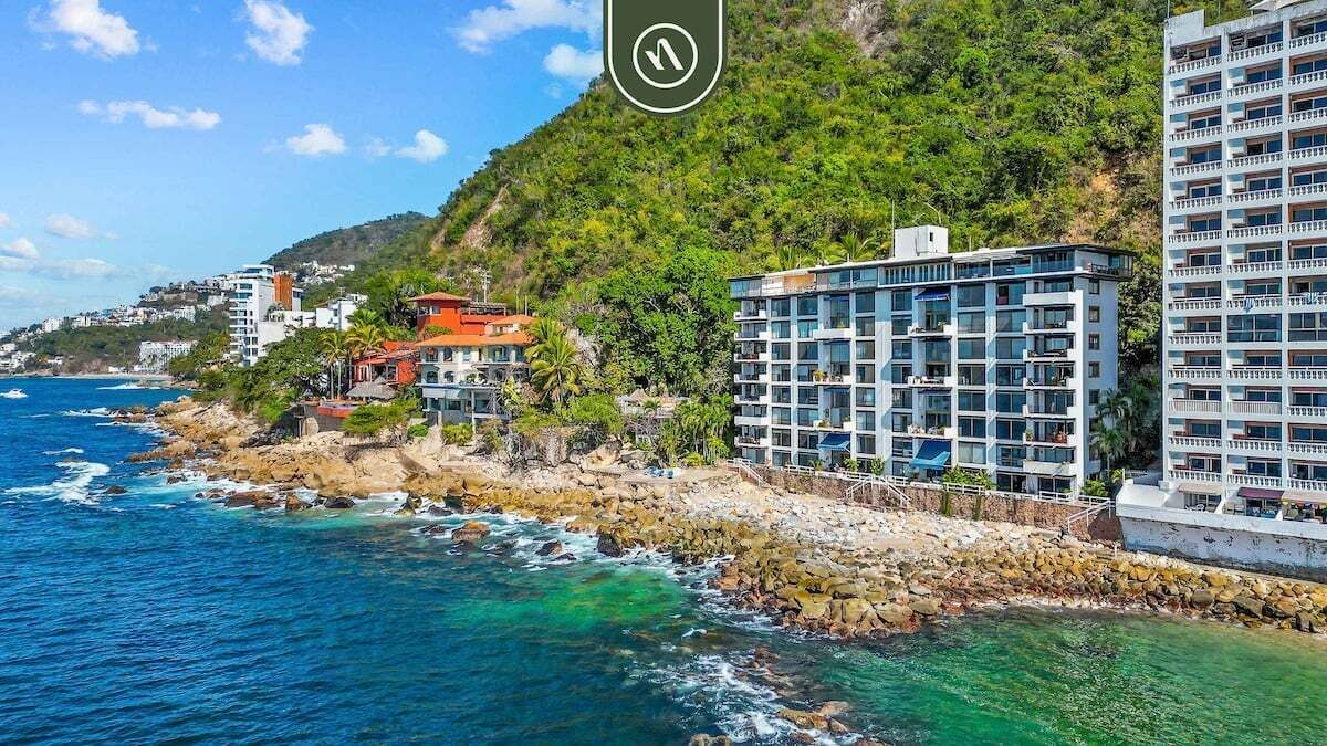 Un hotel a la costa amb diverses plantes, un litoral rocos i vistes a l'oceà.