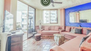 A living room with a pink sofa, a glass coffee table, and a ceiling fan. - Vista del Sol 804 | 2BR/2BA Puerto Vallarta (Puerto Vallarta)