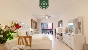 A hotel room with a bed, a dining table with chairs, a TV, and a large mirror. - Playa Royale Tower 1 1133 | 1BR Nuevo Vallarta | Beach, pool & WiFi (Nuevo Vallarta)