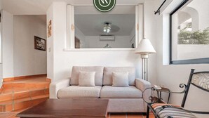 A living room with a sofa, a coffee table, a lamp, and a window with a view.
