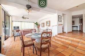 Uma sala de jantar com mesa redonda, cadeiras e ventilador de teto.