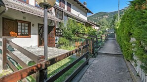 A traditional chalet with a wooden balcony, a stone pathway, and a mountain backdrop. - La Casa Di Dada With Terrace and Garden (Oulx)