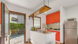A kitchen with a central island, a refrigerator, and a window overlooking a garden. - La Casa Di Dada With Terrace and Garden (Oulx)