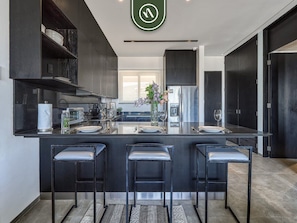 A modern kitchen with a central island, bar stools, and a view of the living area.