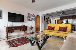 A living room with a sofa, a TV, a desk, and a coffee table.