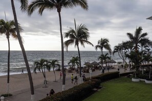 Eine Strandpromenade mit Palmen, einem Strand und einem Restaurantbereich.