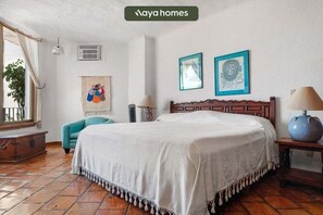 Une chambre à coucher avec un lit, une chaise, une lampe et des œuvres d’art accrochées au mur.
