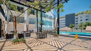 A poolside area with lounge chairs, a table, and a pool. - Cozy 1Br Apt - Pool - GYM - 2 Min to the Beach (Bucerías)