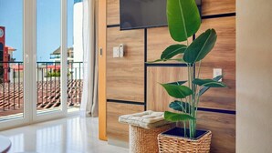A modern room with a large window, a flat-screen TV mounted on the wall, and a potted plant. - Cozy 1Br Apt - Pool - GYM - 2 Min to the Beach (Bucerías)