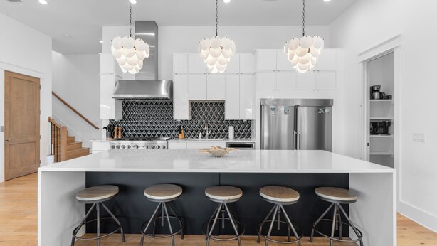 A modern kitchen with a large island, bar stools, stainless steel appliances, and pendant lighting. - Walk to Beach + Pool, Hot Tub & Game Room | 30A Ohana Grande by AvantStay (Santa Rosa Beach)