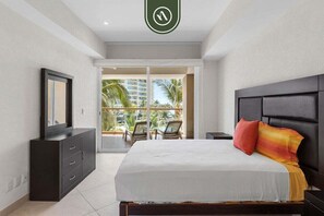 A hotel room with a bed, a dresser, a mirror, and a view of palm trees and buildings.