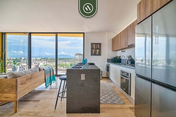 A modern kitchen with a large island, stainless steel appliances, and a view of the city.
