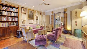 Un salón espacioso con una estantería de madera, un sofá rosa y un ventilador de techo.