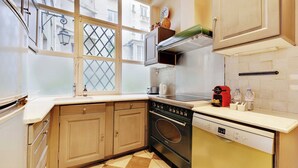 Cocina compacta con armarios de madera, horno integrado y ventana con vistas a la ciudad.