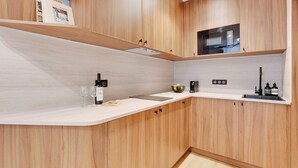 Una cocina moderna con armarios de madera, un microondas y una botella de vino en la encimera.
