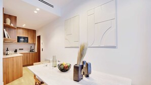 Una cocina moderna con armarios de madera, un microondas y una zona de comedor con una mesa y sillas blancas.