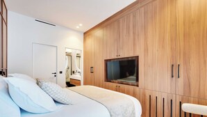 Un dormitorio moderno con una cama grande, un armario de madera y un televisor.