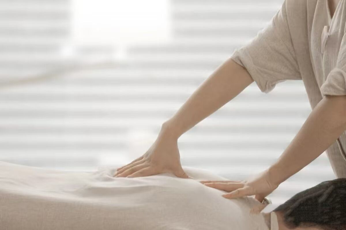 En person får massage i en säng i ett rum med en randig vägg.