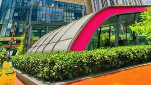 Two tall buildings with reflective glass facades, a curved structure with a pink accent, and a clear blue sky with clouds. - M Panda Tower Boutique Hotel (Chengdu)