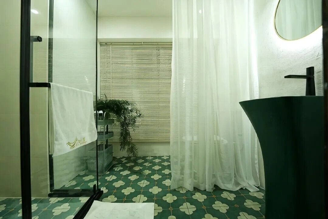 Un baño con cabina de ducha de vidrio, un lavabo con grifo moderno y una ventana con persianas.
