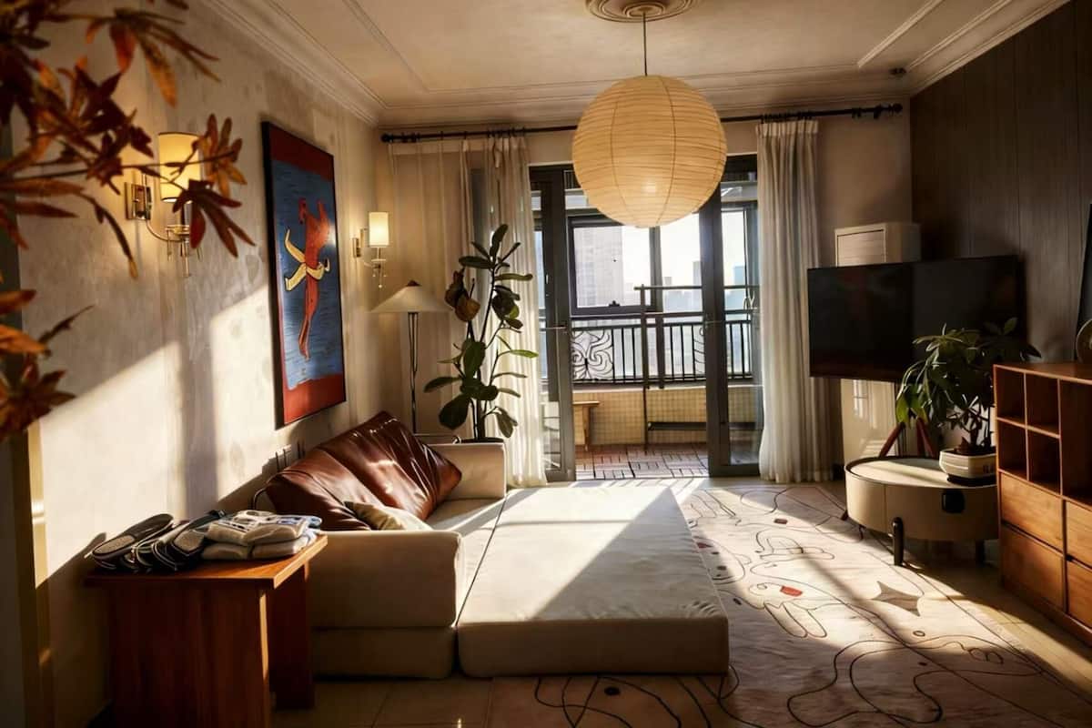 A modern living room with a sofa, a coffee table, a TV, and a large window with a view of the city.