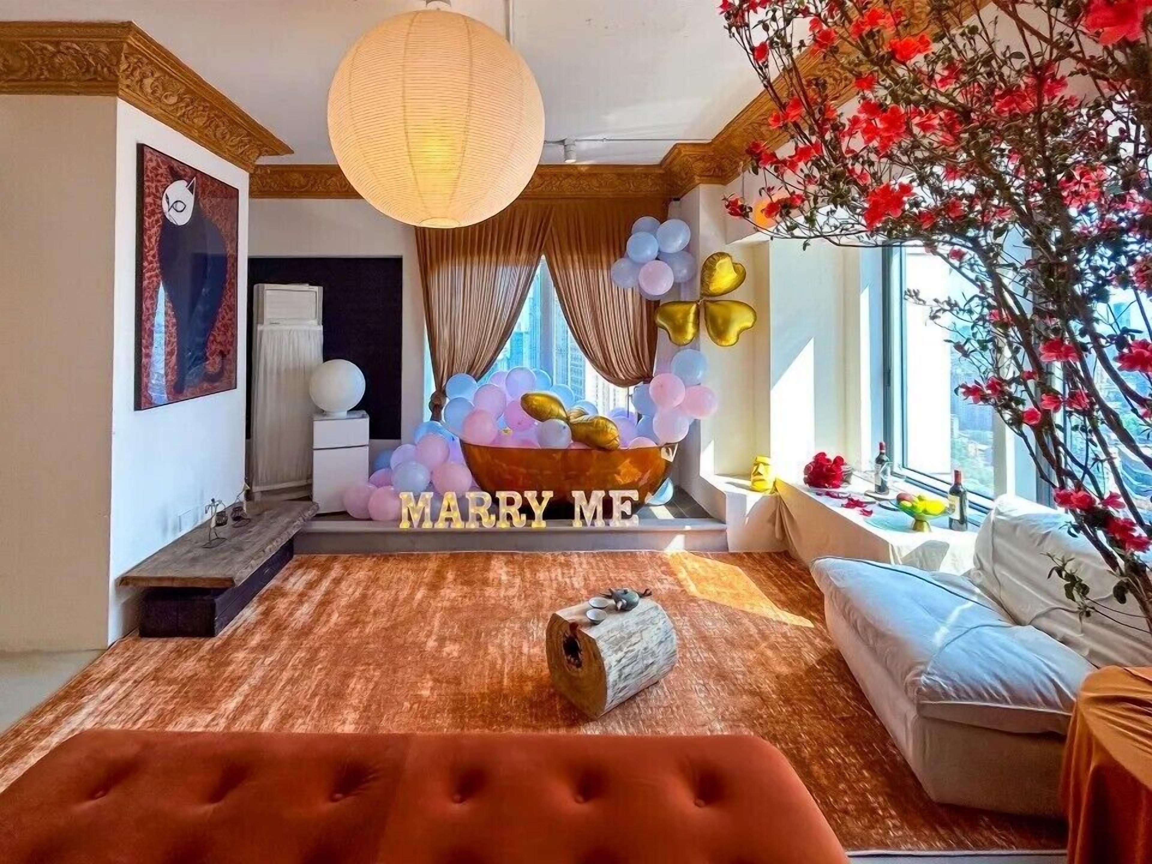 Una habitación con sofá, un adorno central y un cartel que dice 'MARRY ME'.
