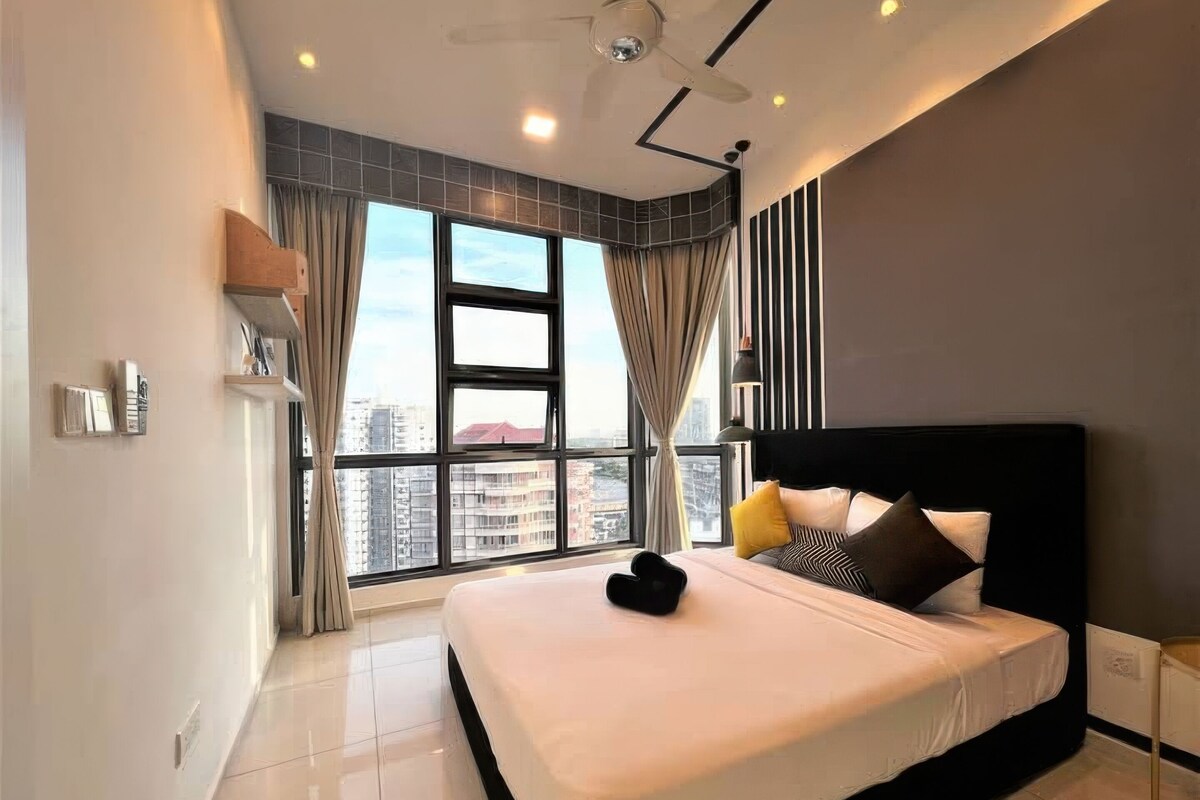 Una camera da letto moderna con un grande letto, una ventola a soffitto e vista sulla città attraverso ampie finestre.